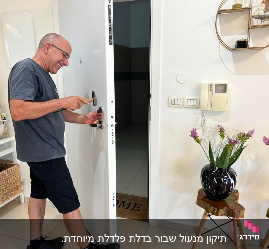 אדם מתקן מנעול דלת עם פטיש